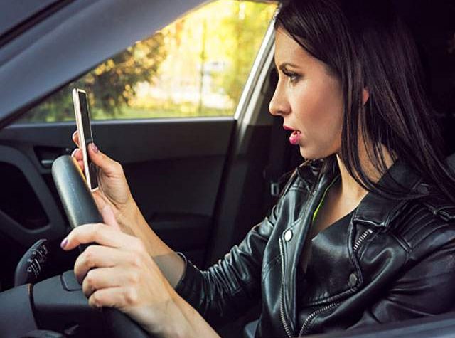 mujer con móvil en la mano conduciendo